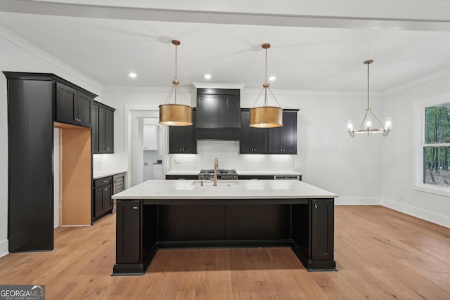 kitchen featuring hanging light fixtures, light wood-type flooring, and a center island with sink