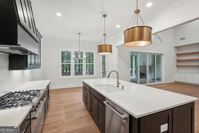 kitchen featuring sink, stainless steel appliances, light stone counters, a center island with sink, and decorative light fixtures