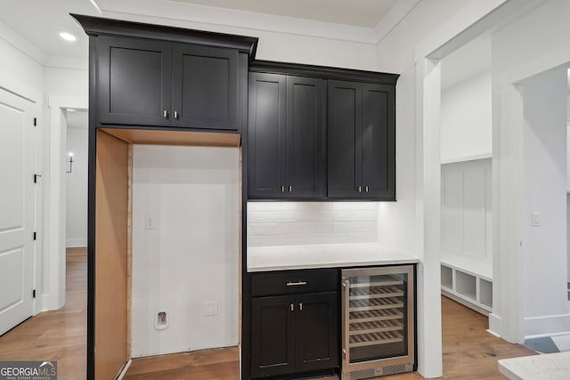 kitchen featuring wine cooler, ornamental molding, light hardwood / wood-style floors, and backsplash