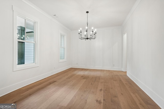 unfurnished dining area featuring ornamental molding, an inviting chandelier, and light hardwood / wood-style flooring