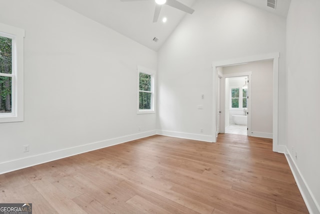 empty room with high vaulted ceiling, a healthy amount of sunlight, and light wood-type flooring