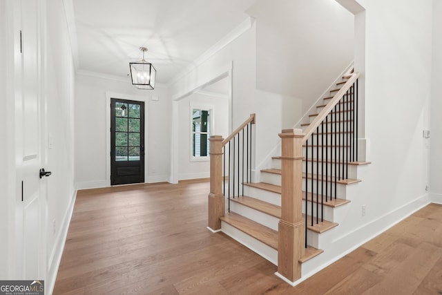 foyer entrance with crown molding, an inviting chandelier, and light hardwood / wood-style flooring