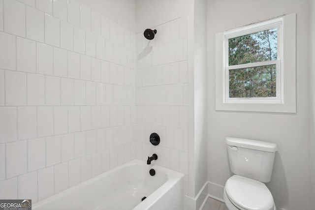 bathroom featuring toilet and tiled shower / bath