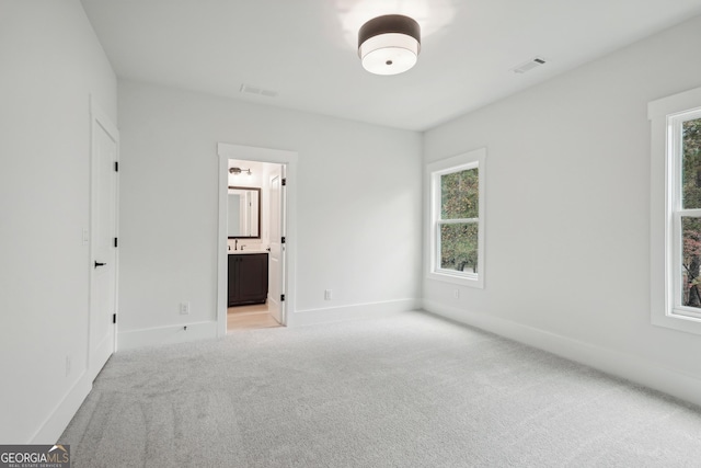 unfurnished bedroom featuring ensuite bath and light colored carpet