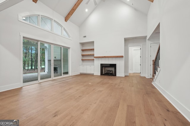 unfurnished living room featuring high vaulted ceiling, beamed ceiling, and light wood-type flooring