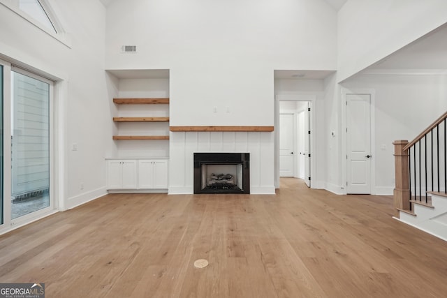 unfurnished living room featuring a towering ceiling and light hardwood / wood-style flooring