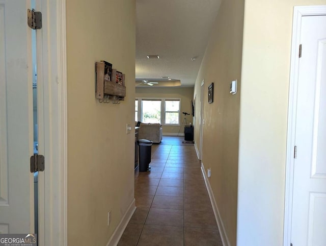 corridor with dark tile patterned flooring and a textured ceiling