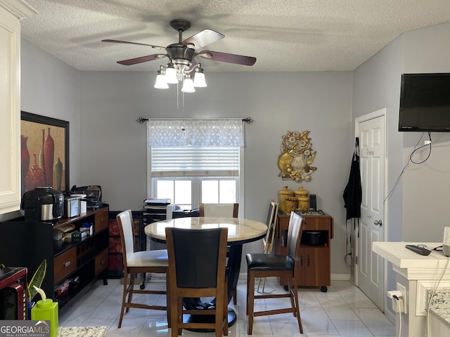 tiled dining room featuring ceiling fan and a textured ceiling