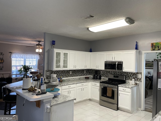 kitchen featuring white cabinetry, light stone counters, decorative backsplash, and stainless steel appliances