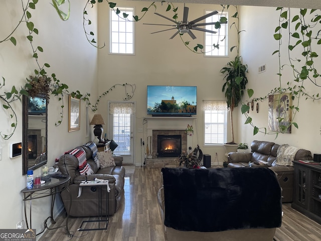 living room with a towering ceiling, hardwood / wood-style floors, and ceiling fan