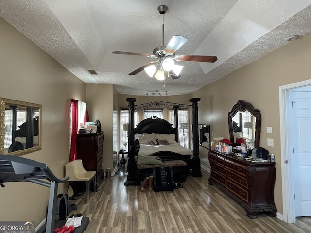 bedroom with ceiling fan, hardwood / wood-style floors, and a textured ceiling