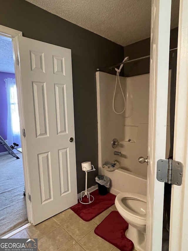 bathroom featuring tile patterned flooring, bathtub / shower combination, a textured ceiling, and toilet