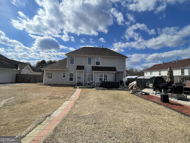 rear view of property with a patio, a yard, and a jacuzzi