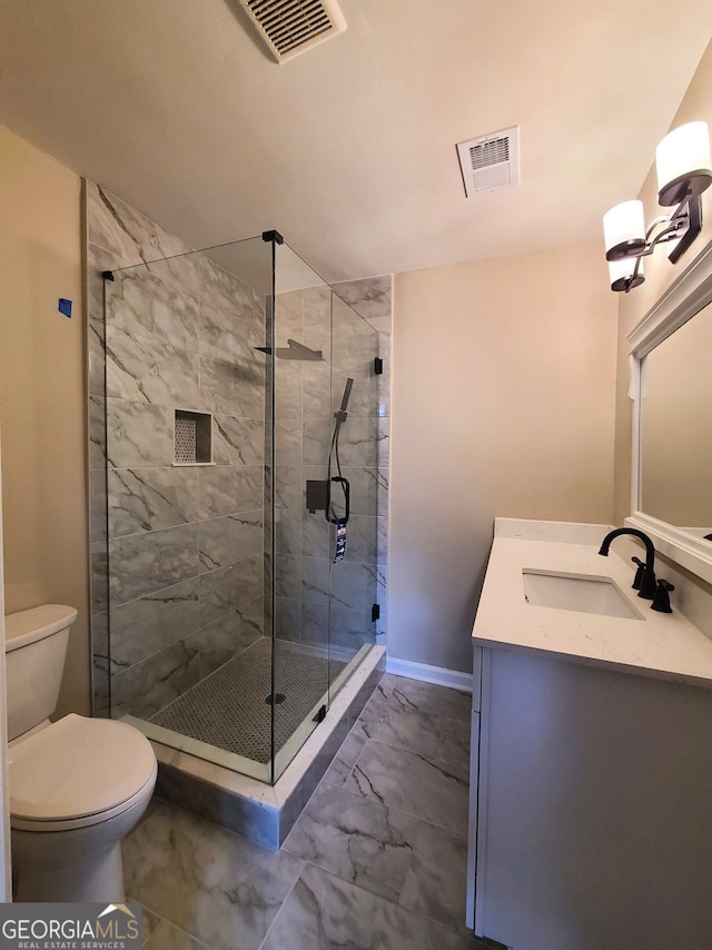 bathroom featuring a shower with door, vanity, and toilet