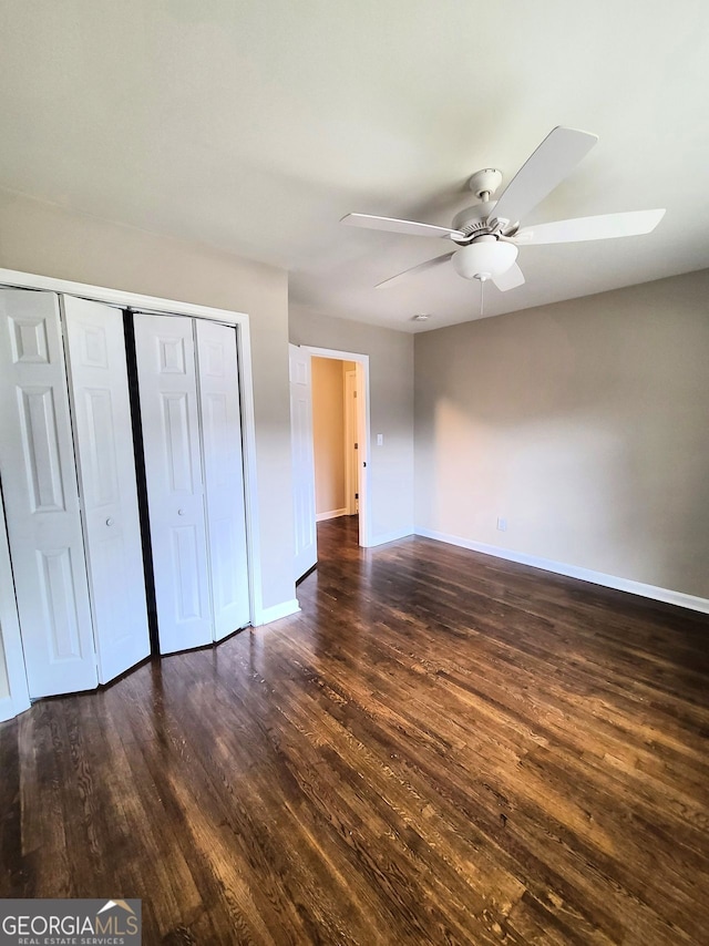 unfurnished bedroom with dark wood-type flooring, ceiling fan, and a closet