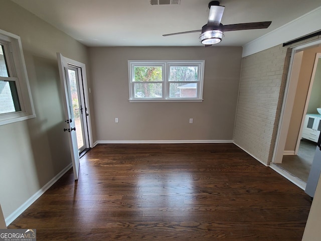 interior space featuring dark wood-type flooring, ceiling fan, and brick wall