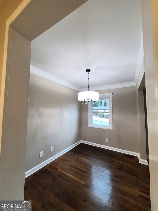 spare room with ornamental molding, dark hardwood / wood-style floors, and a chandelier