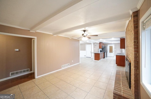 unfurnished living room featuring light tile patterned flooring, sink, beam ceiling, ceiling fan, and a fireplace