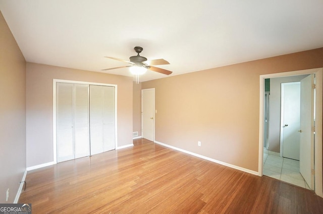 unfurnished bedroom featuring ceiling fan, a closet, and light wood-type flooring