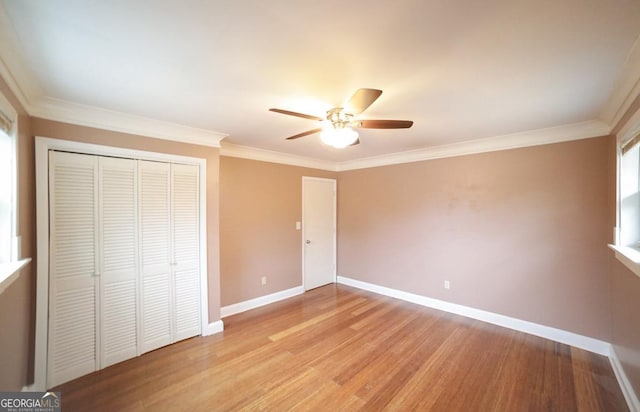 unfurnished bedroom featuring crown molding, ceiling fan, light hardwood / wood-style floors, and a closet