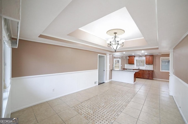 kitchen featuring light tile patterned floors, kitchen peninsula, and a tray ceiling