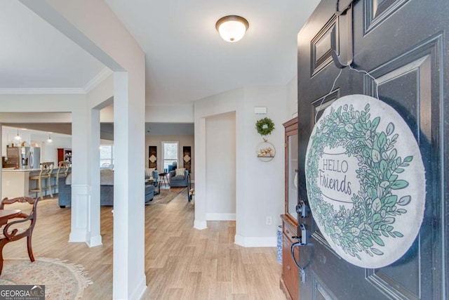 foyer entrance featuring crown molding and light hardwood / wood-style floors