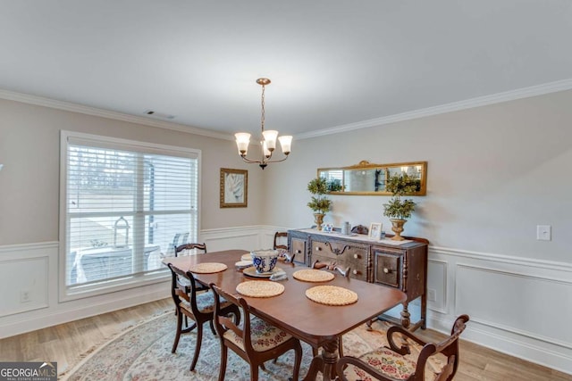 dining room featuring crown molding, light hardwood / wood-style flooring, and a notable chandelier