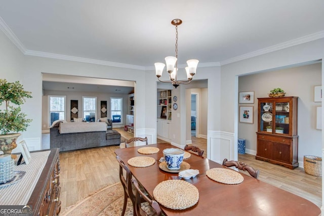 dining room featuring crown molding, a chandelier, and light wood-type flooring