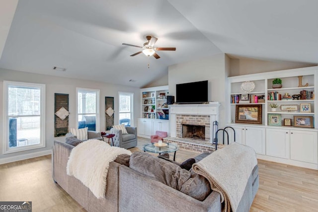 living room featuring ceiling fan, lofted ceiling, a fireplace, and light wood-type flooring