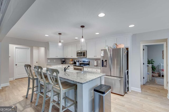 kitchen featuring white cabinetry, hanging light fixtures, light stone counters, and stainless steel appliances