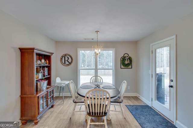 dining space with a notable chandelier and light hardwood / wood-style floors