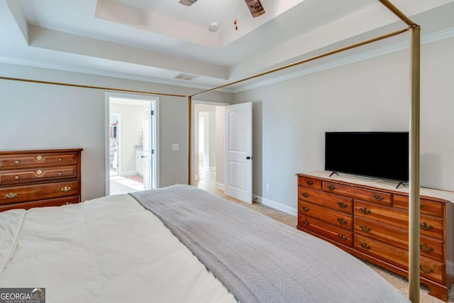 bedroom featuring ceiling fan, connected bathroom, a tray ceiling, ornamental molding, and light colored carpet