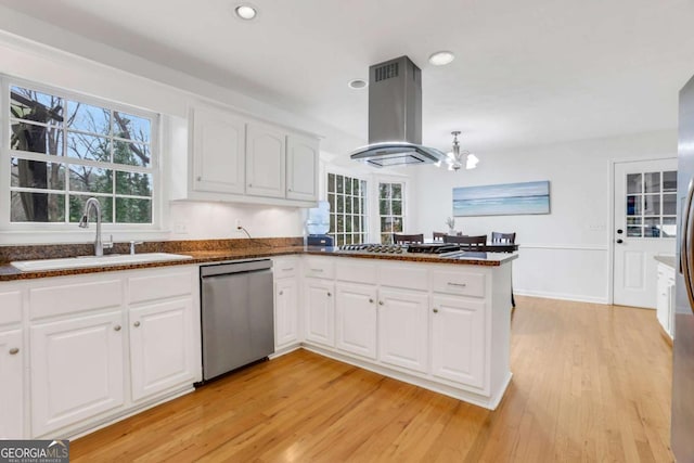 kitchen with sink, appliances with stainless steel finishes, white cabinetry, island exhaust hood, and kitchen peninsula