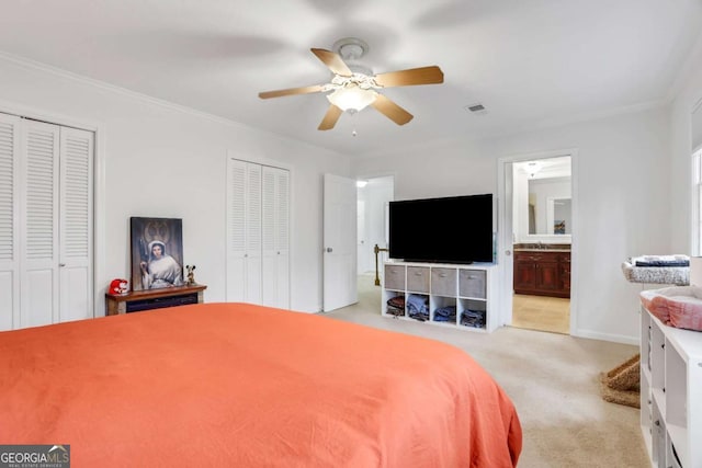 carpeted bedroom with multiple closets, ceiling fan, and ensuite bath