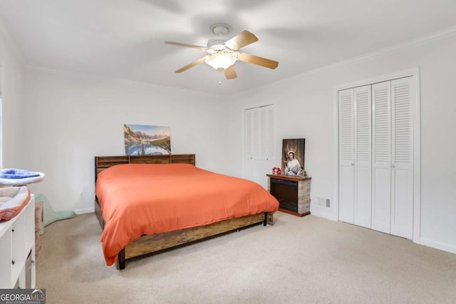 carpeted bedroom with multiple closets, ornamental molding, and ceiling fan