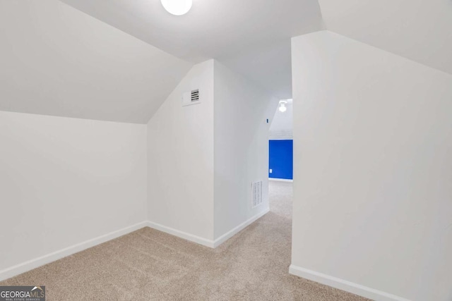 additional living space with vaulted ceiling and light carpet