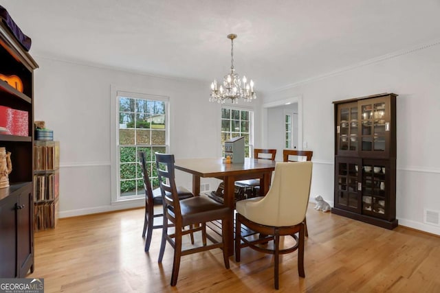 dining space with ornamental molding, a chandelier, and light hardwood / wood-style floors