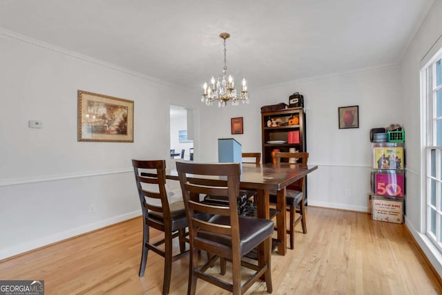 dining area featuring an inviting chandelier, ornamental molding, and light hardwood / wood-style floors