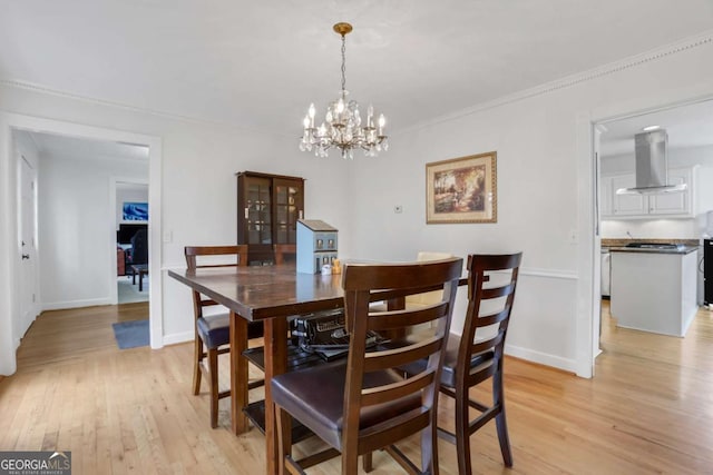 dining room with ornamental molding, light hardwood / wood-style flooring, and a notable chandelier