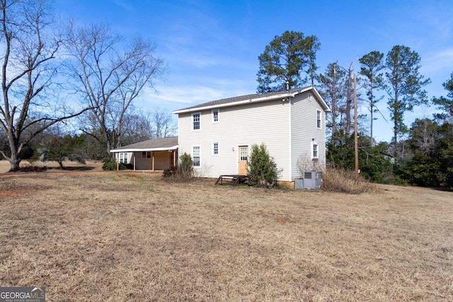 rear view of property with a lawn and central air condition unit