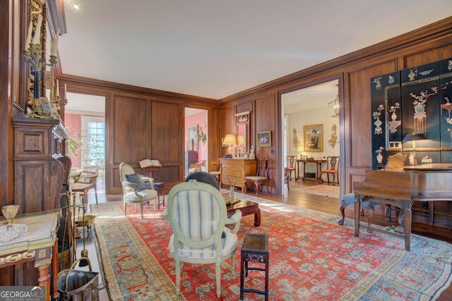 living room with ornamental molding and wood walls