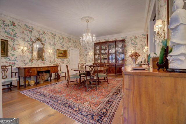 dining area with hardwood / wood-style floors, crown molding, and a chandelier