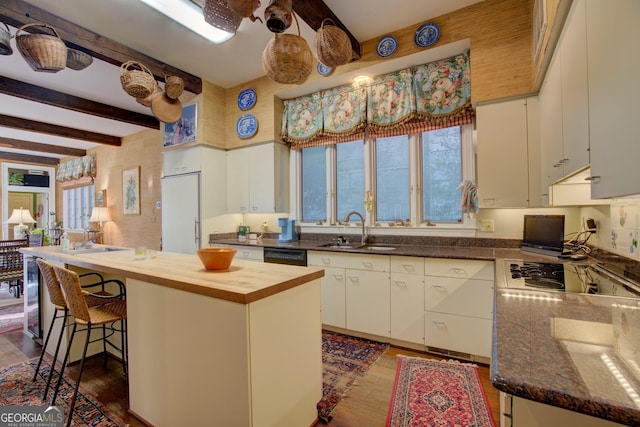 kitchen with white built in refrigerator, sink, white cabinetry, a center island, and beamed ceiling