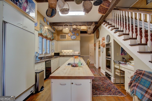 kitchen with butcher block countertops, light hardwood / wood-style floors, white cabinets, and a kitchen island