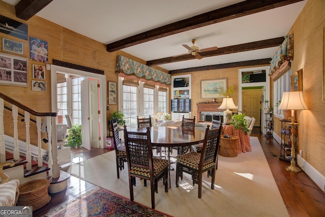 dining room featuring a premium fireplace, ceiling fan, and beam ceiling