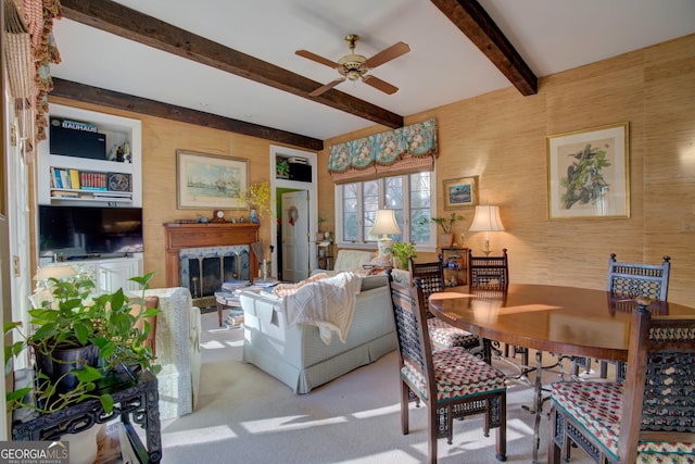 living room featuring built in features, ceiling fan, a high end fireplace, light carpet, and beamed ceiling