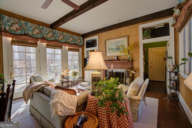 living room with ceiling fan, a premium fireplace, and beamed ceiling