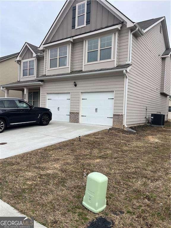 view of front of house featuring a garage, a front yard, and central AC unit