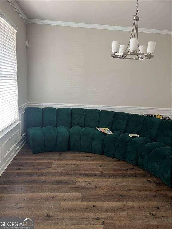 living room with crown molding, dark wood-type flooring, and a chandelier