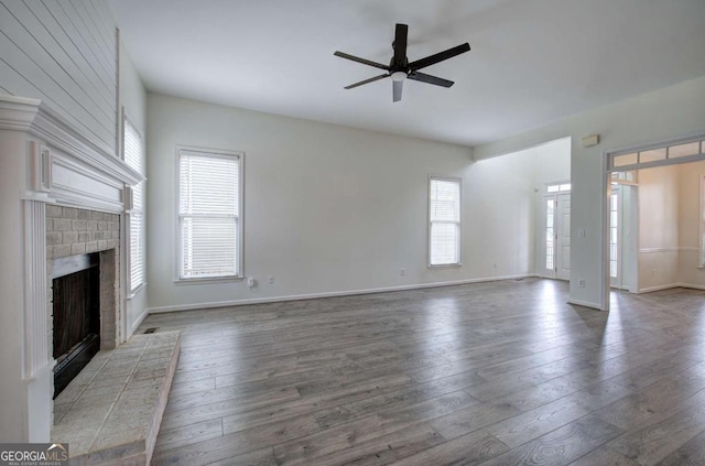 unfurnished living room with a fireplace, dark wood-type flooring, and ceiling fan